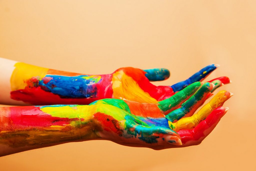 Painted hands, colorful fun. Creative, funny and artistic means happy! Orange background wall